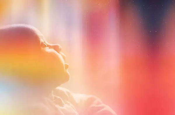 A photograph of a baby staring up in wonder at the night sky