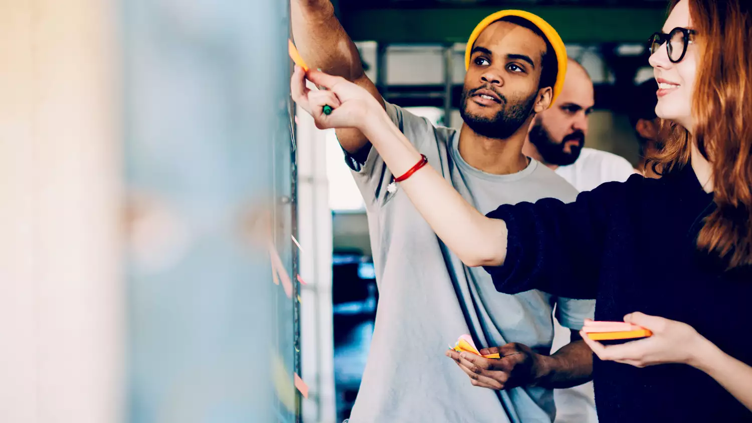 Two people stick post-its on a whiteboard