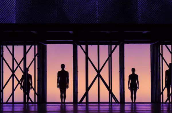 Four silhouettes on a stage with purple light behind them.