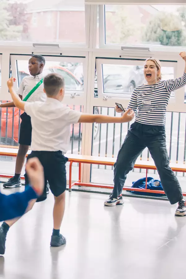 A school session with an adult female in an expressive pose front of schoolchildren