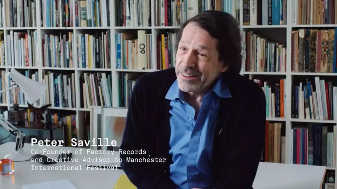 Designer Peter Saville in front of a bookshelf