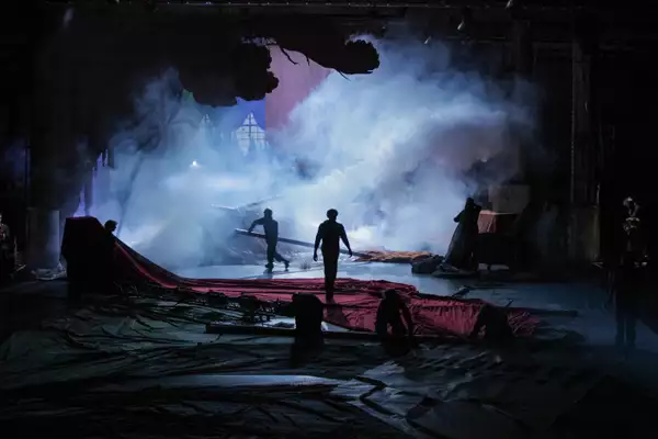 A stage set with silhouettes of people and smoke in the background