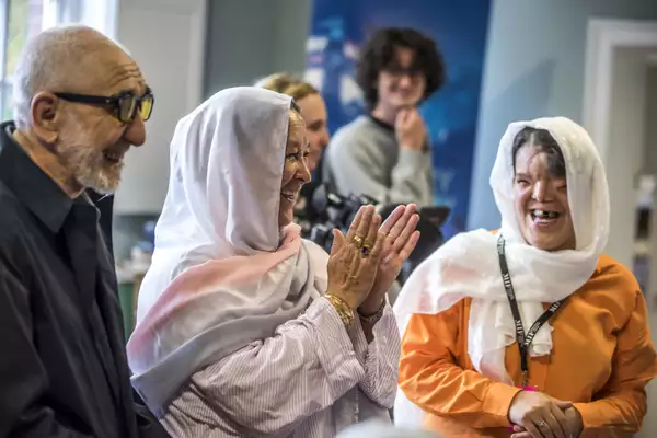 three people chatting and laughing at a community event