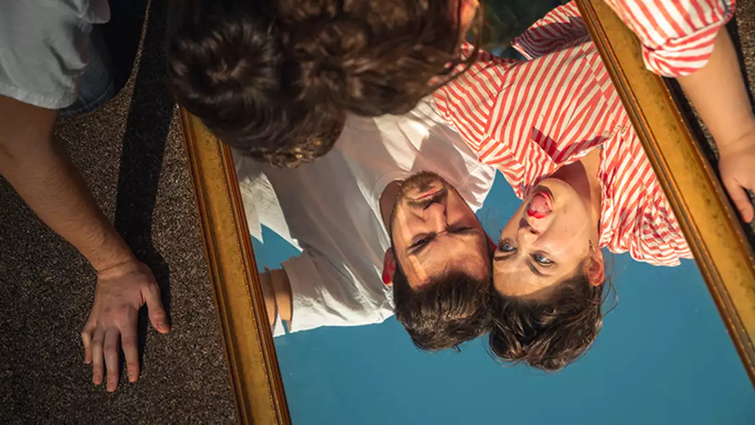 two people who looking into a mirrow upside down pulling fiunny faces